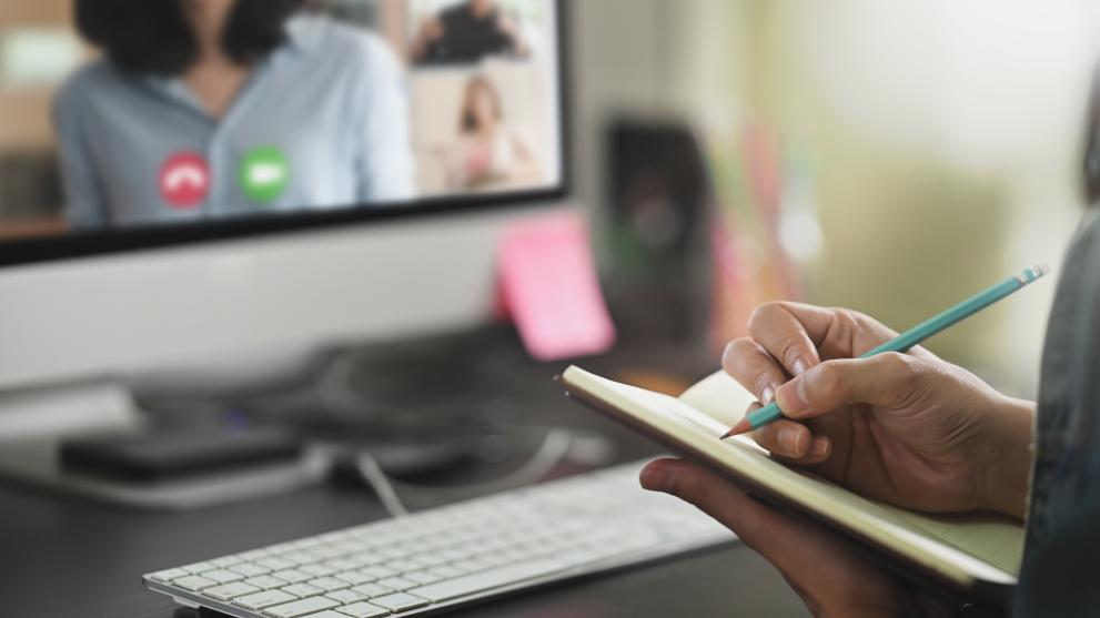Closeup of man taking notes sitting in front of a computer